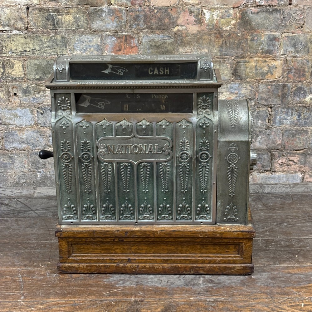 An early twentieth-century mechanical cash register featuring a cast metal case on a wooden base with an open currency drawer. View VII