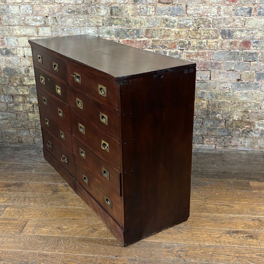 A 1920s mahogany bank of ten drawers featuring inset brass campaign handles and a solid plinth base. View V