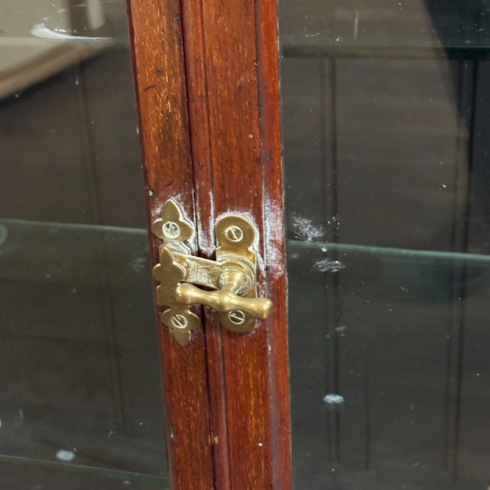 A 1920s dark oak countertop display cabinet featuring twin glazed doors with a central brass catch and internal shelving. View III