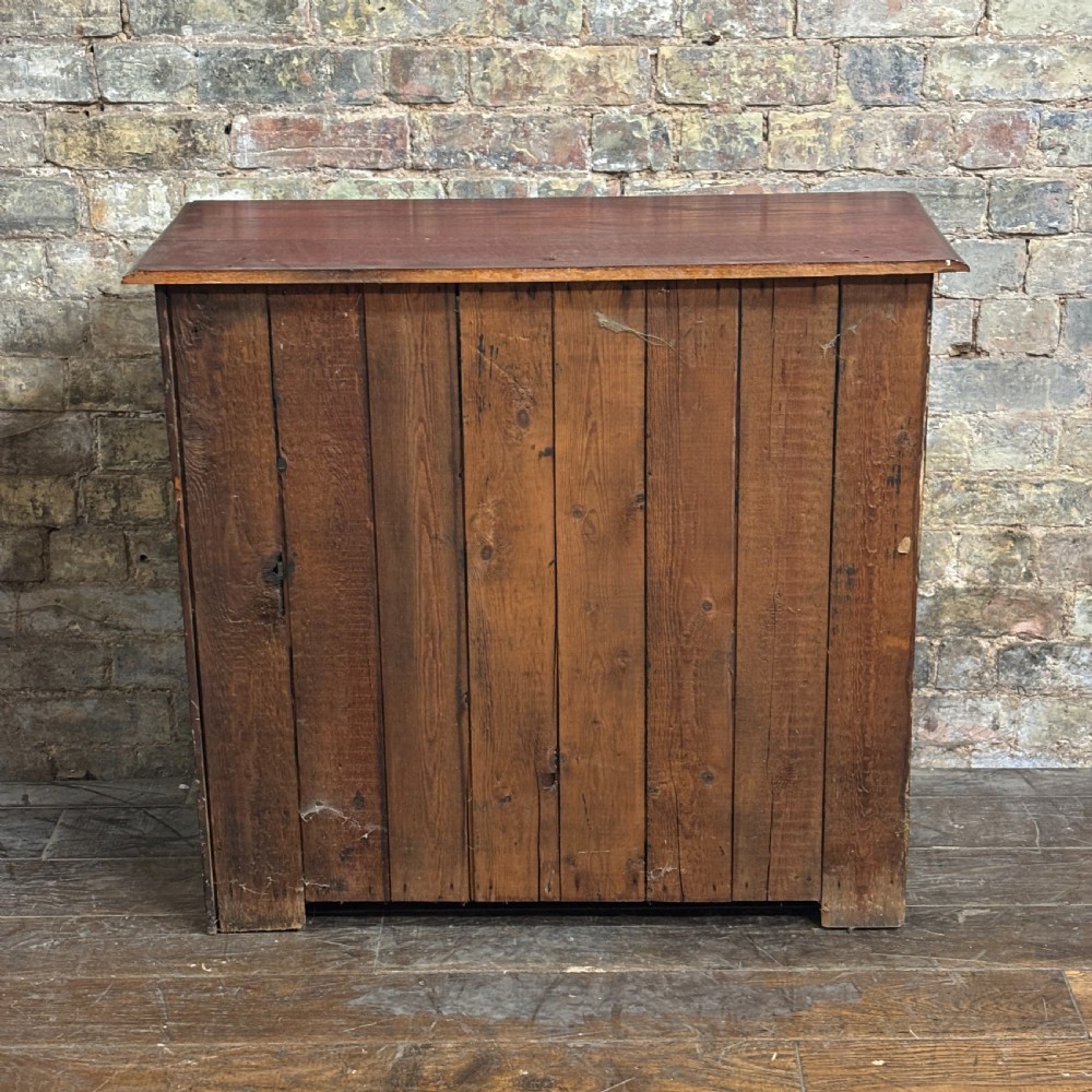 A 1920s dark oak countertop display cabinet featuring twin glazed doors with a central brass catch and internal shelving. View VII