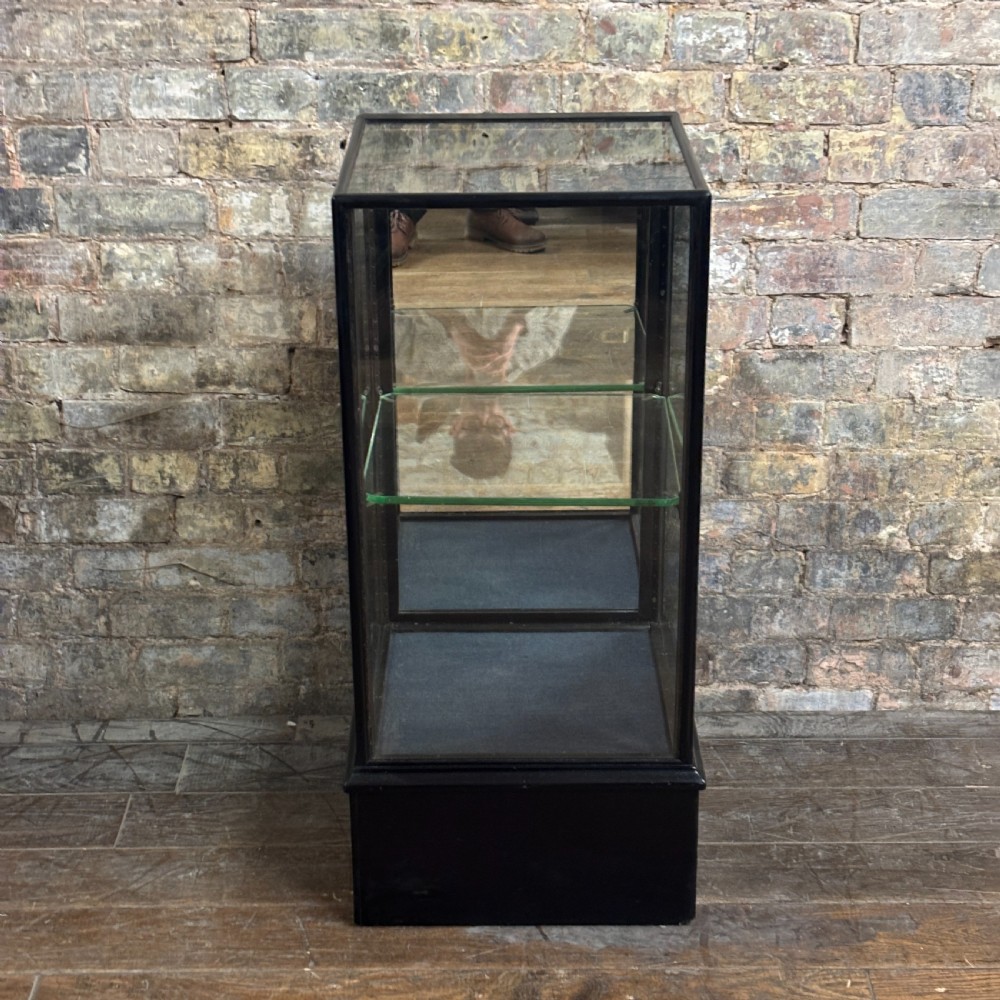 A vertical ebonised wooden countertop display cabinet featuring glazed sides, a central glass shelf, and a mirrored back. View II