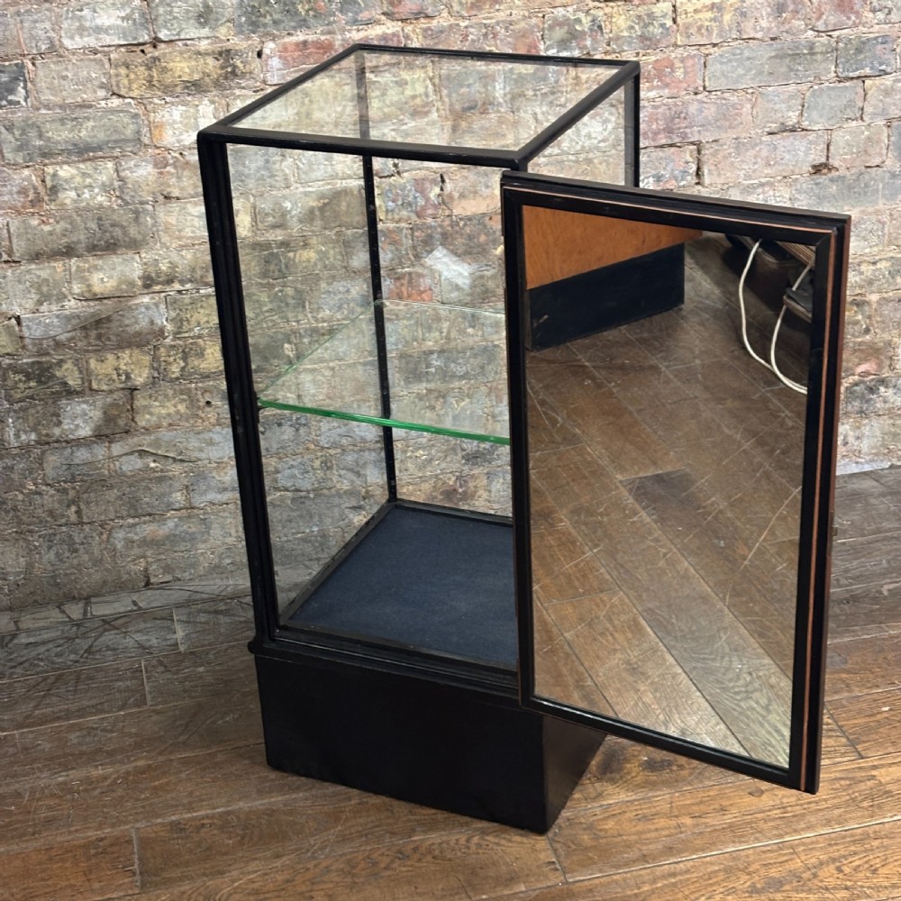 A vertical ebonised wooden countertop display cabinet featuring glazed sides, a central glass shelf, and a mirrored back. View III