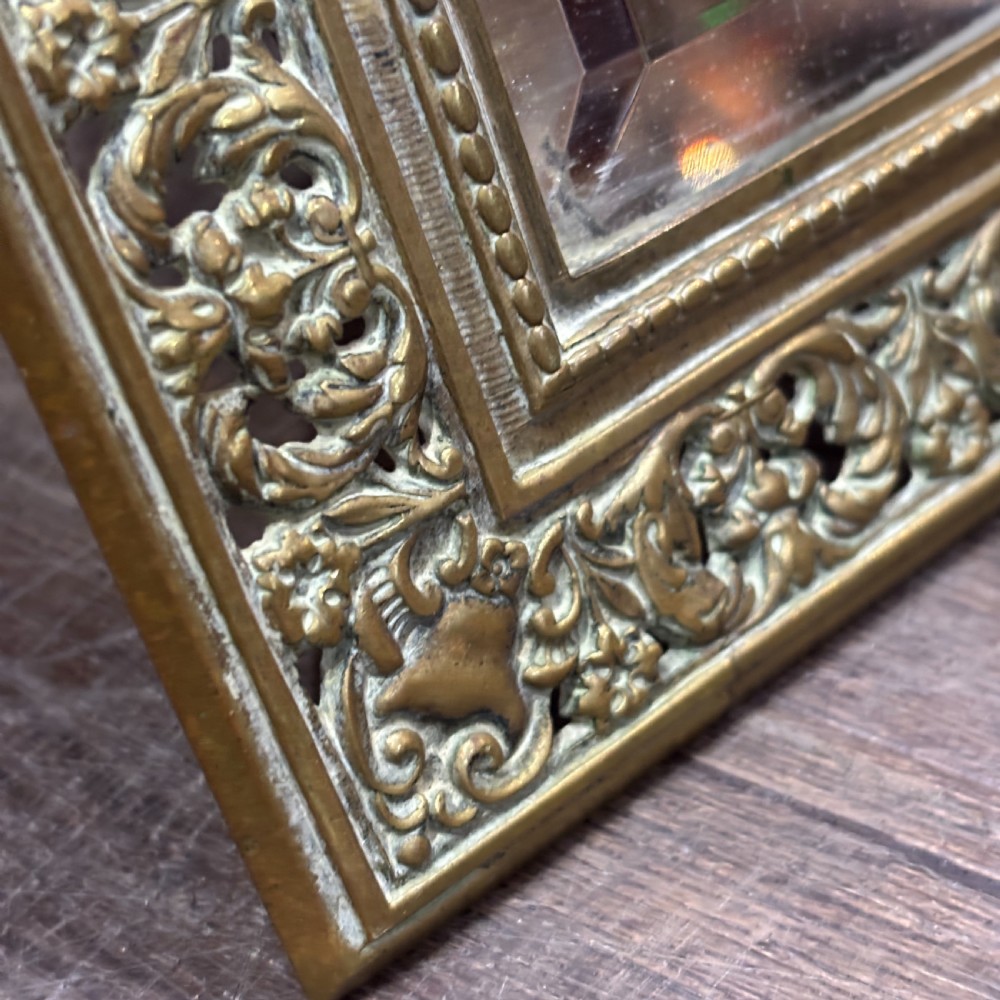 An ornate late nineteenth-century French brass table mirror featuring a crowned crest, relief scrollwork border, and a rectangular bevelled glass plate. View VI