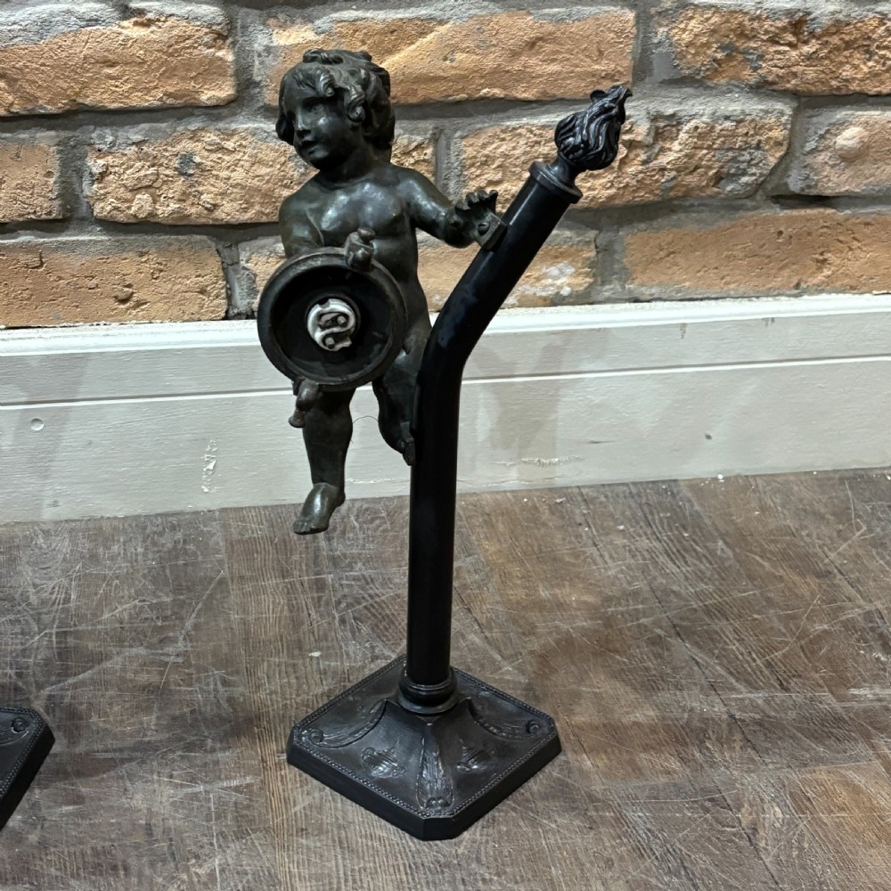 A pair of dark patinated bronze torchere table lamps featuring sculpted cherub figures mounted on decorative square bases. View III