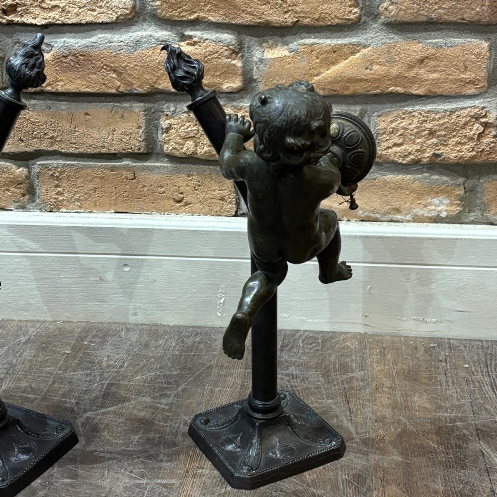 A pair of dark patinated bronze torchere table lamps featuring sculpted cherub figures mounted on decorative square bases. View IV