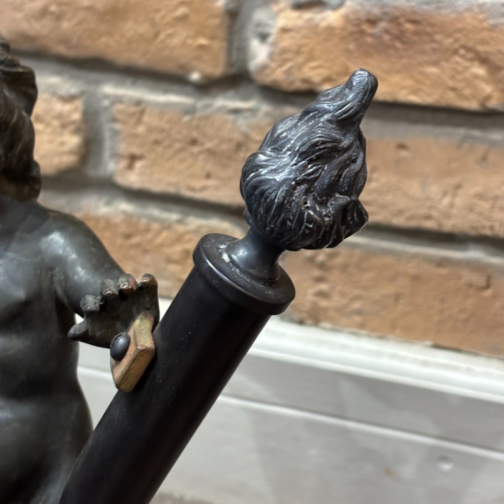 A pair of dark patinated bronze torchere table lamps featuring sculpted cherub figures mounted on decorative square bases. View V
