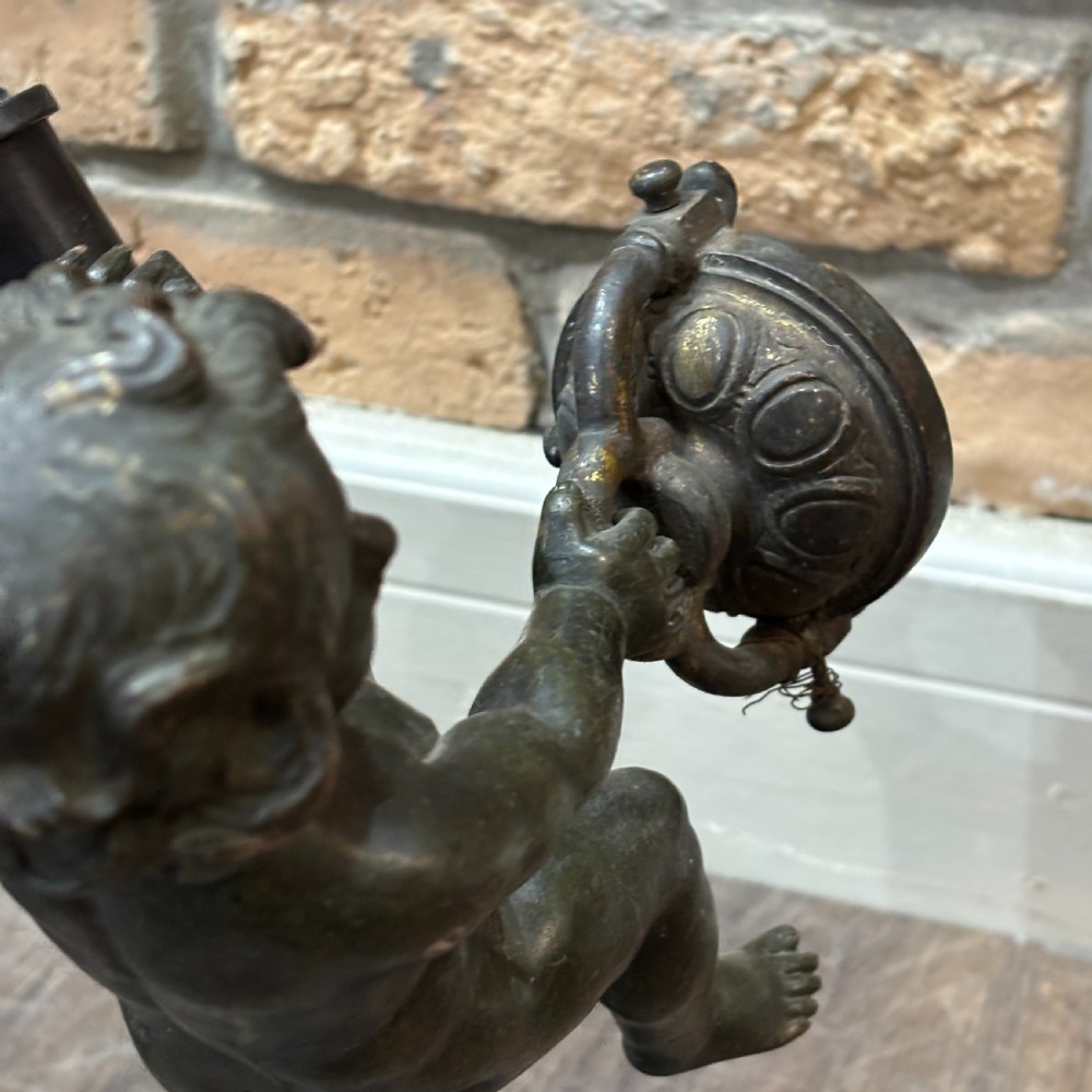 A pair of dark patinated bronze torchere table lamps featuring sculpted cherub figures mounted on decorative square bases. View VI