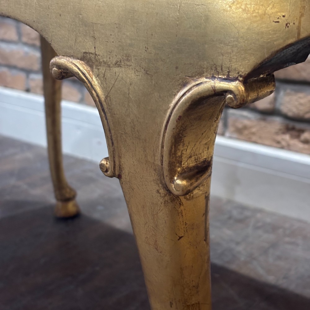 A gilded 1910s oval glass display counter featuring curved side panels and cabriole legs ending in hoof feet. View VI