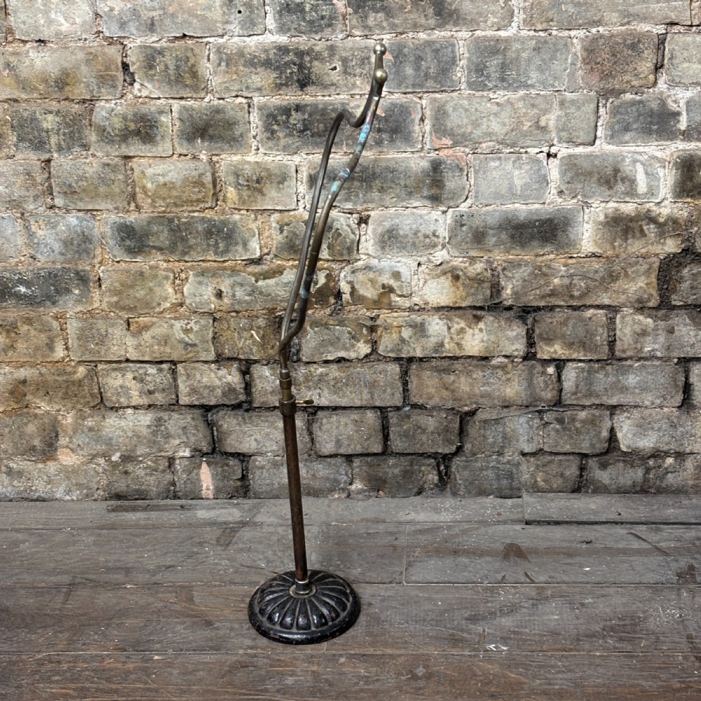 An early 20th-century brass drapers display stand featuring a wire bust frame on an adjustable central column with a heavy fluted cast iron base. View V