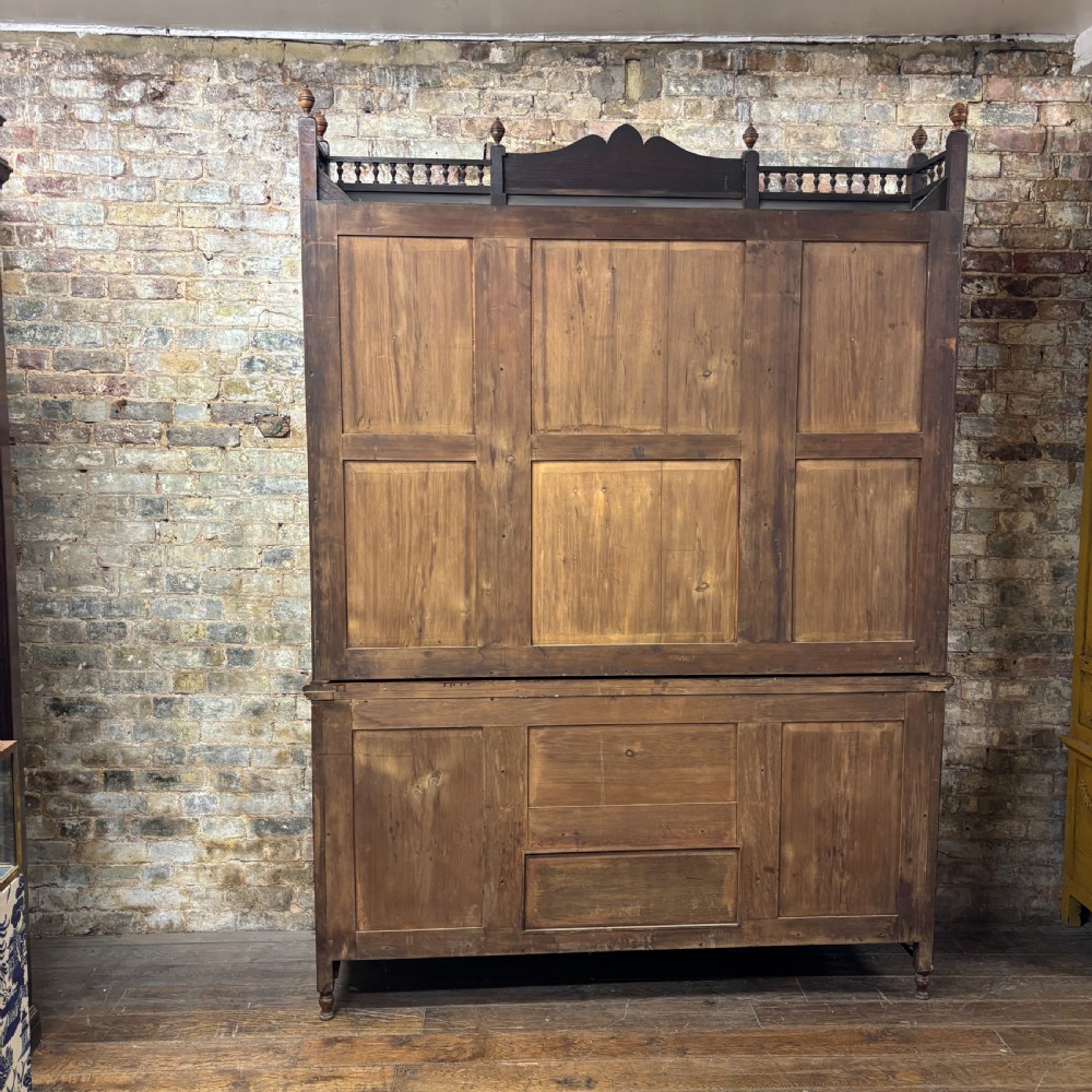 A large Victorian carved oak display cabinet featuring three glazed upper doors, a spindle gallery rail, and panelled lower cupboard doors. View II