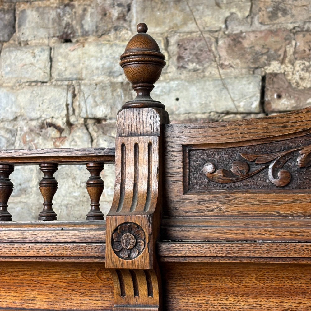 A large Victorian carved oak display cabinet featuring three glazed upper doors, a spindle gallery rail, and panelled lower cupboard doors. View V