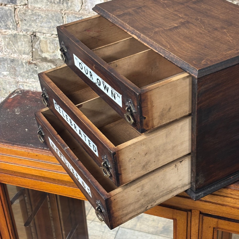 A dark oak three-drawer tabletop drapers cabinet featuring hand-painted commercial typography and brass drop handles. View V
