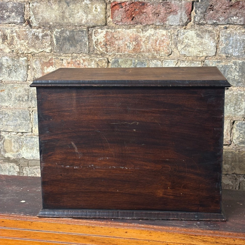 A dark oak three-drawer tabletop drapers cabinet featuring hand-painted commercial typography and brass drop handles. View VI