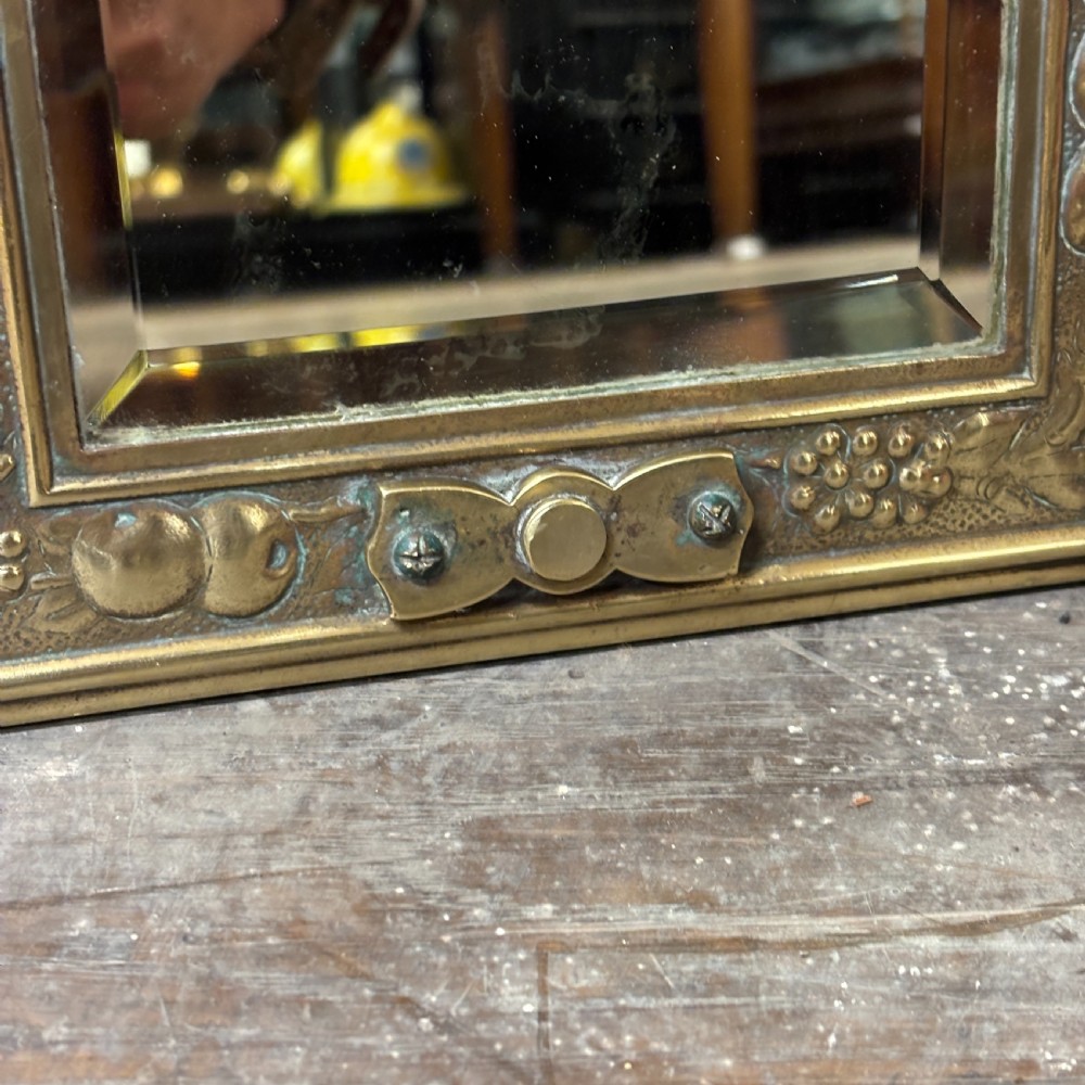 A rectangular Edwardian dressing table mirror with an embossed brass frame featuring fruit motifs surrounding bevelled mirror glass. View III