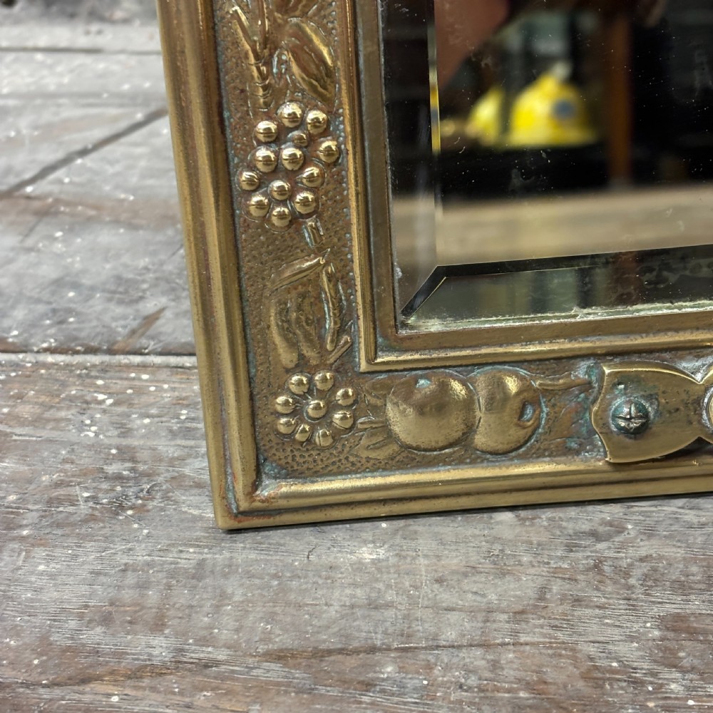 A rectangular Edwardian dressing table mirror with an embossed brass frame featuring fruit motifs surrounding bevelled mirror glass. View V