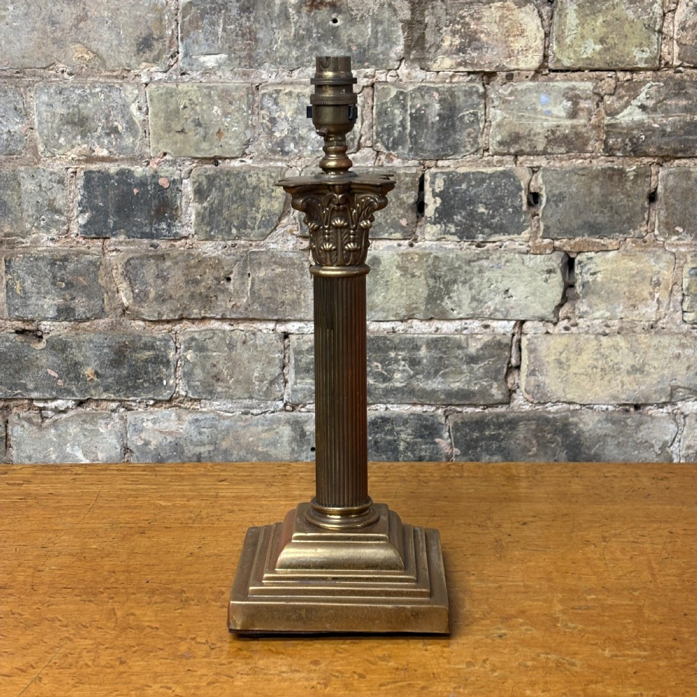A cast brass table lamp base designed in the form of a fluted Corinthian column on a stepped square plinth.