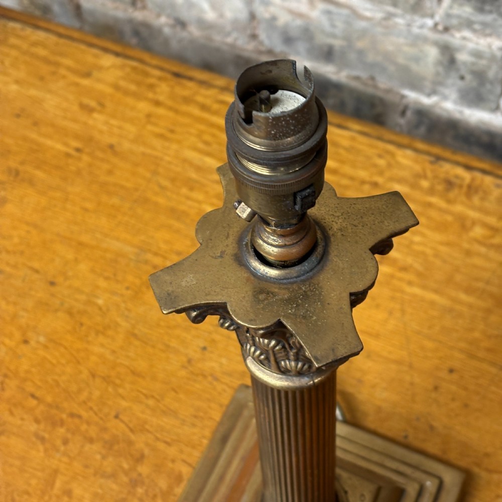 A cast brass table lamp base designed in the form of a fluted Corinthian column on a stepped square plinth. View II