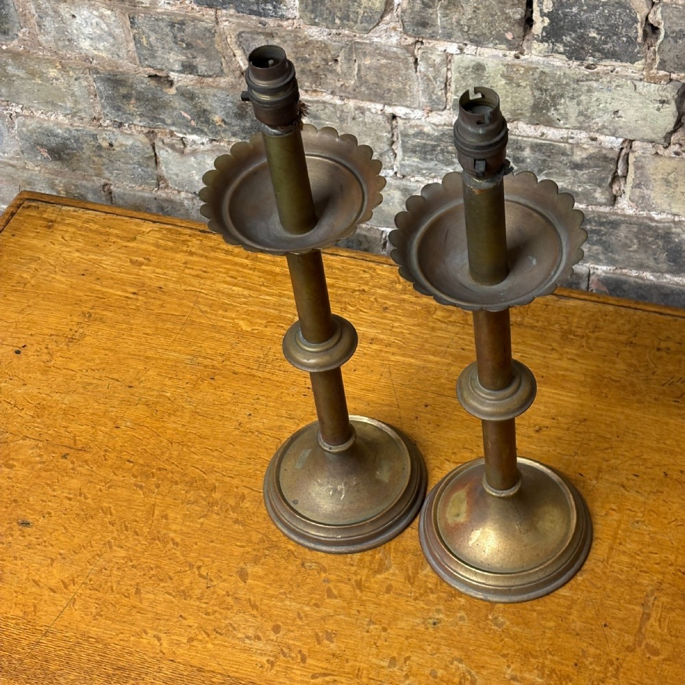 A pair of early 20th-century brass candlestick table lamps with scalloped drip trays, turned stems, and circular stepped bases. View II