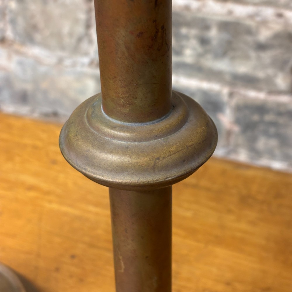 A pair of early 20th-century brass candlestick table lamps with scalloped drip trays, turned stems, and circular stepped bases. View IV