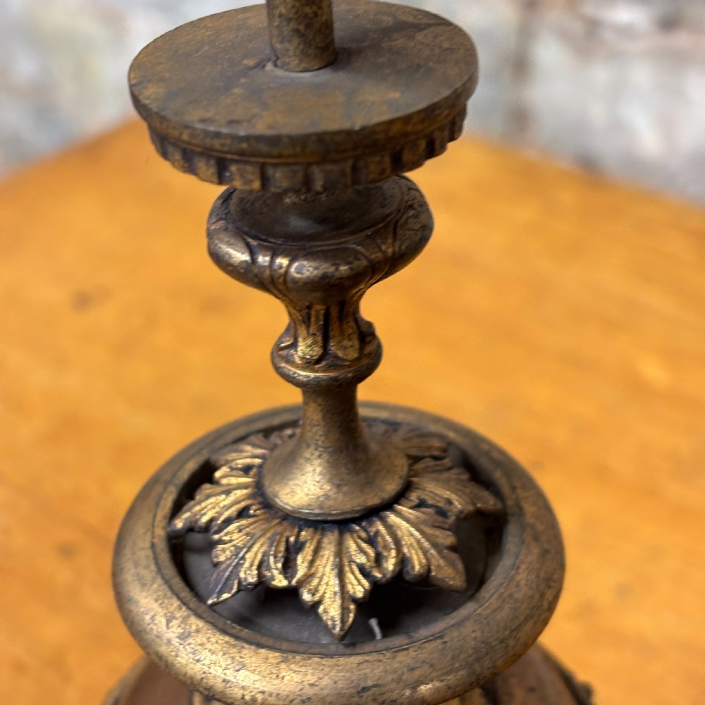 An antique cast brass candlestick featuring an urn-shaped central section with relief mask details, a stepped turned stem, and a fluted nozzle. View IV