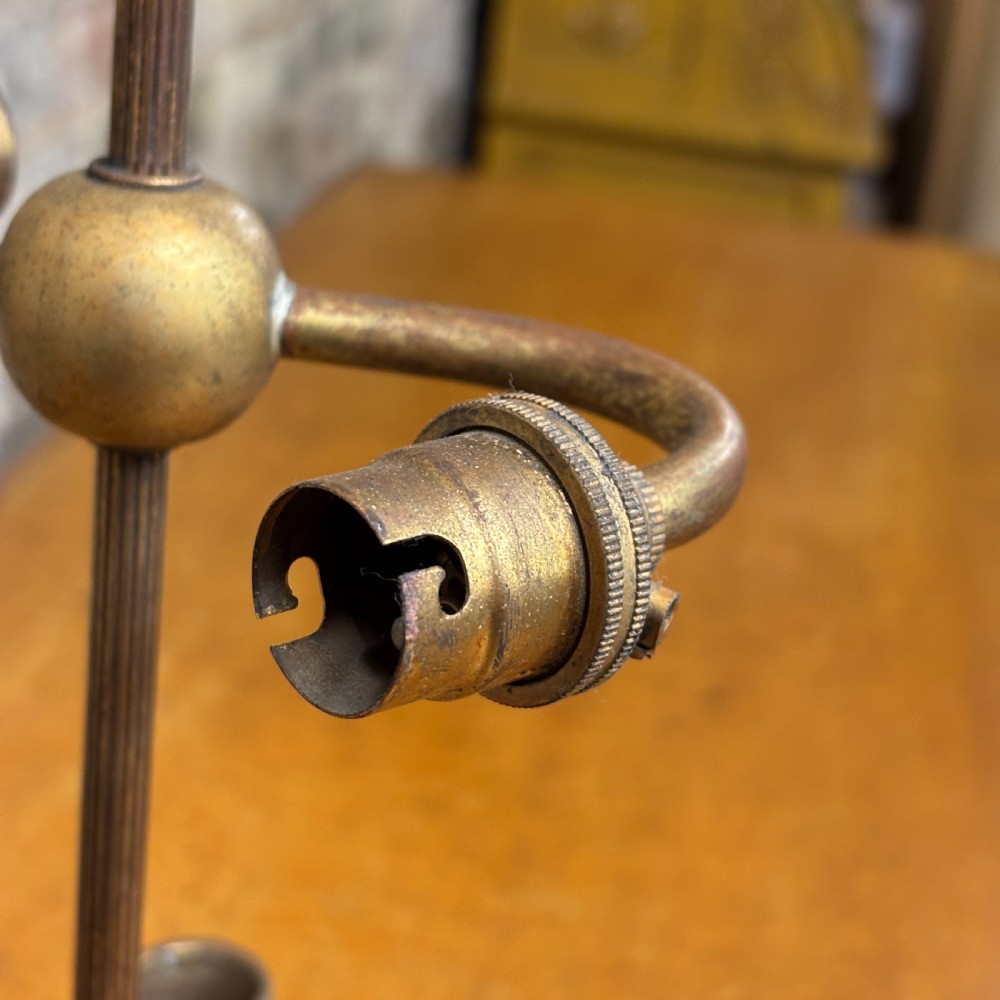 An antique cast brass candelabra table lamp featuring a scrolled base, twin candle sconces, two electrical fittings, and a finial top. View IV