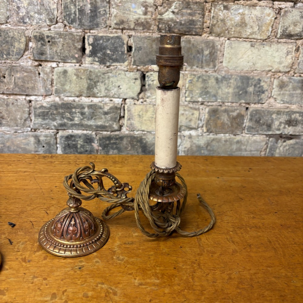 A pair of early 20th-century cast brass wall sconces featuring ornate scrollwork arms, gadrooned backplates, and cream-coloured candle sleeves. View II