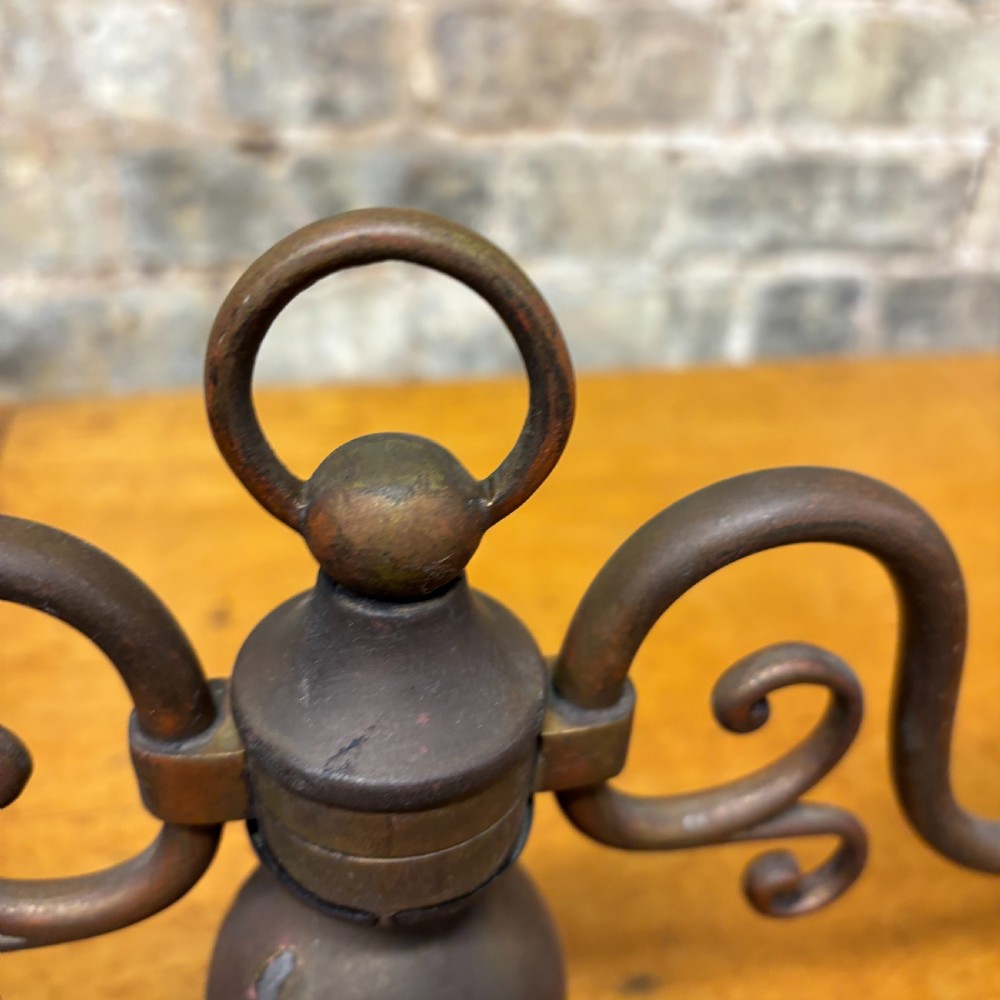 An early 20th-century patinated brass two-arm candelabra table lamp featuring curved scroll arms, faux candle sleeves, and a stepped circular base. View IV