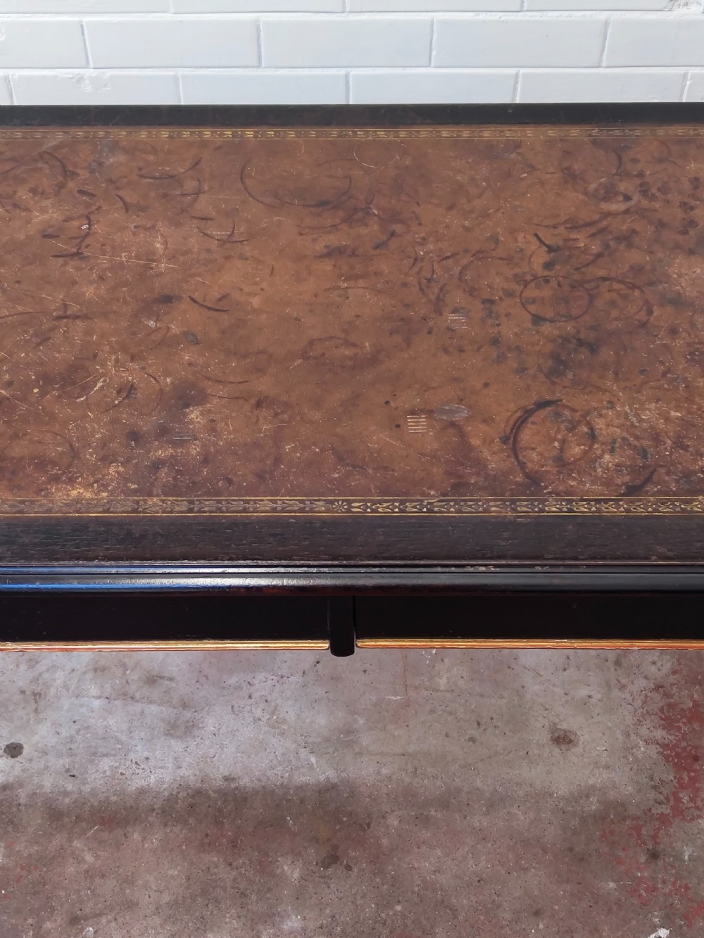 A Victorian Aesthetic Movement ebonised writing table featuring a brown leather inset top, fluted legs with gilt detailing, and brass castors. View X