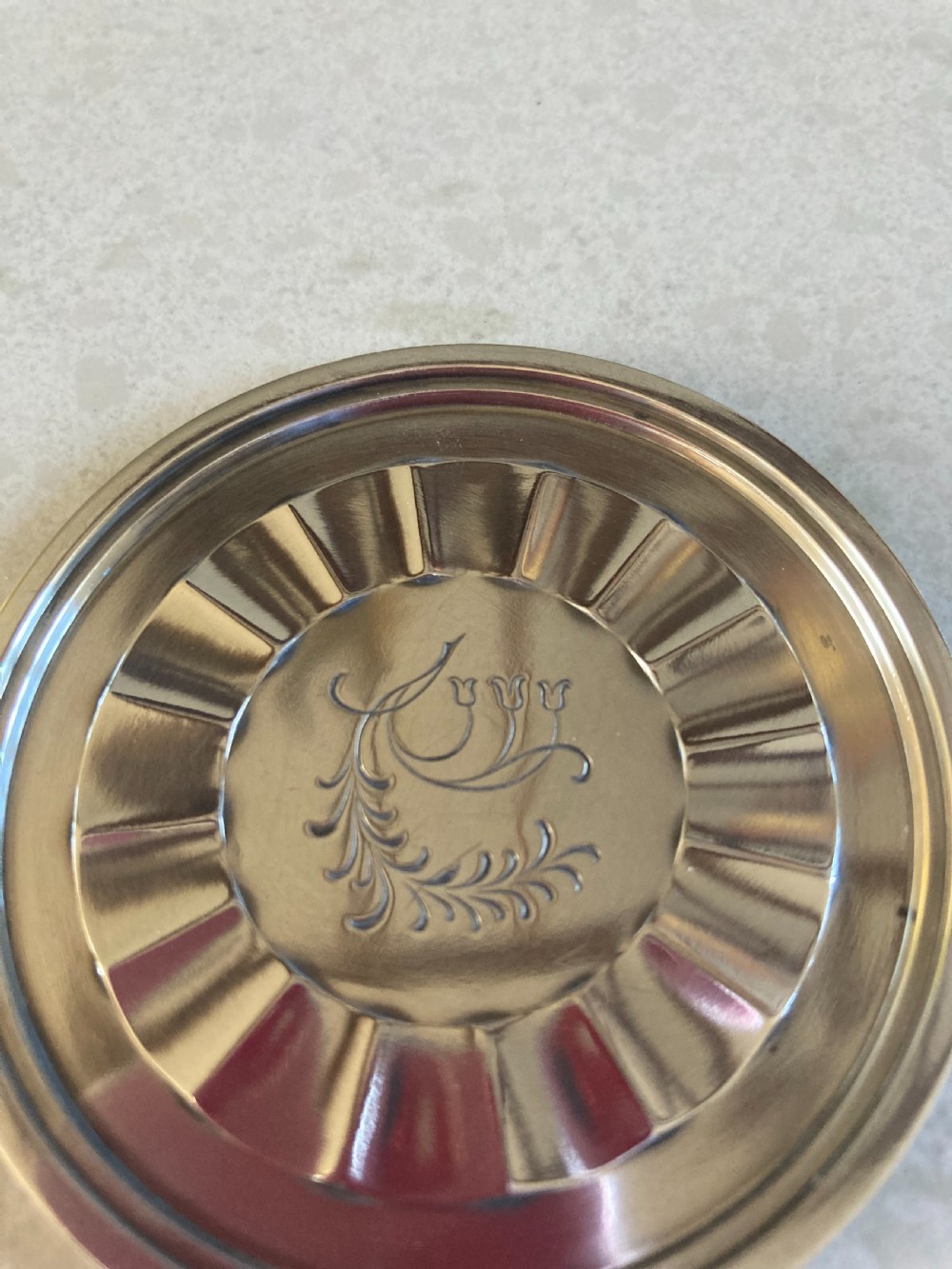 A circular silver coaster featuring a fluted inner rim and an engraved botanical floral design in the centre. View II