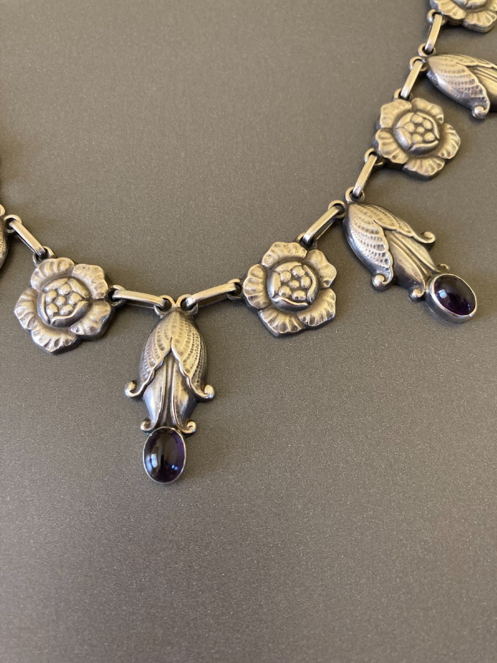 A Danish sterling silver Art Nouveau necklace featuring sculpted floral links and dangling cabochon amethyst gemstones. View II