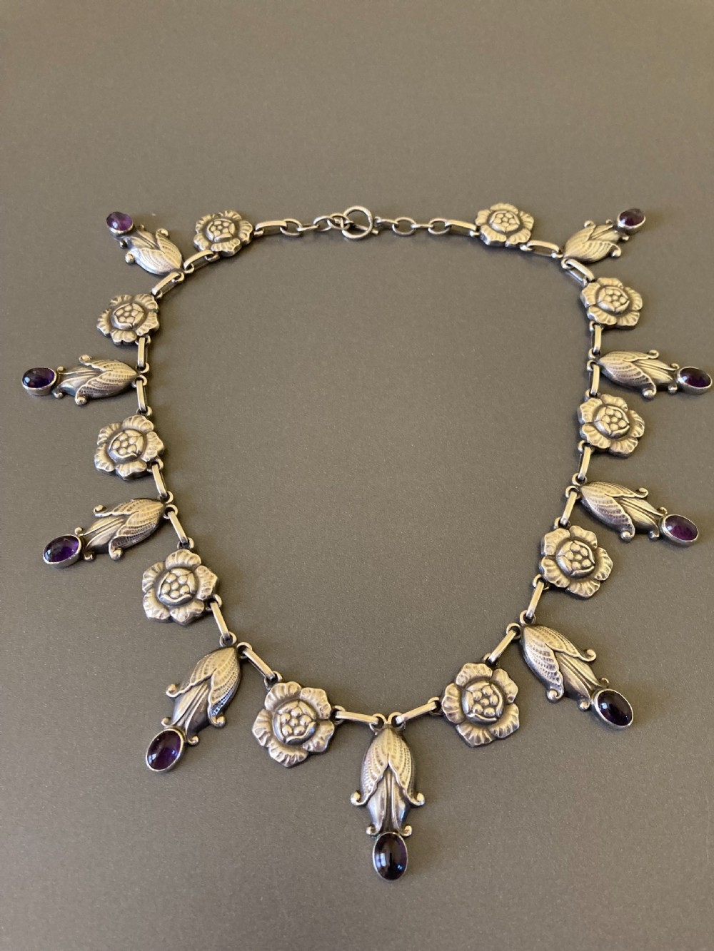 A Danish sterling silver Art Nouveau necklace featuring sculpted floral links and dangling cabochon amethyst gemstones. View III