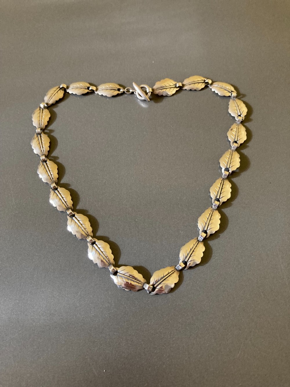A vintage Danish silver necklace composed of linked leaf-shaped sterling silver segments arranged in a circular chain.