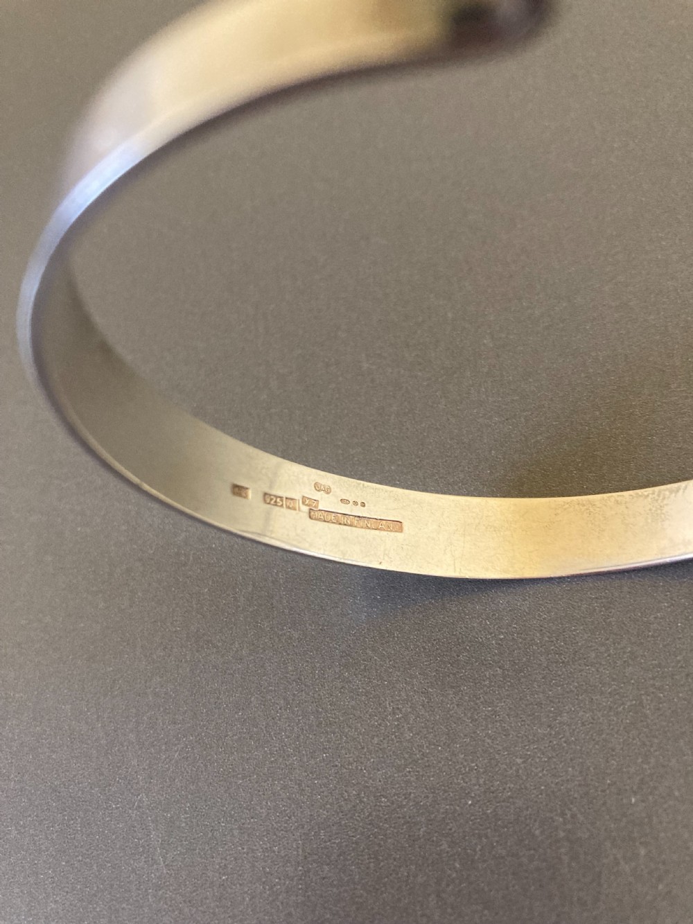 A hinged silver bangle features a central circular frame holding a cabochon rutilated quartz gemstone with needle-like inclusions. View VI