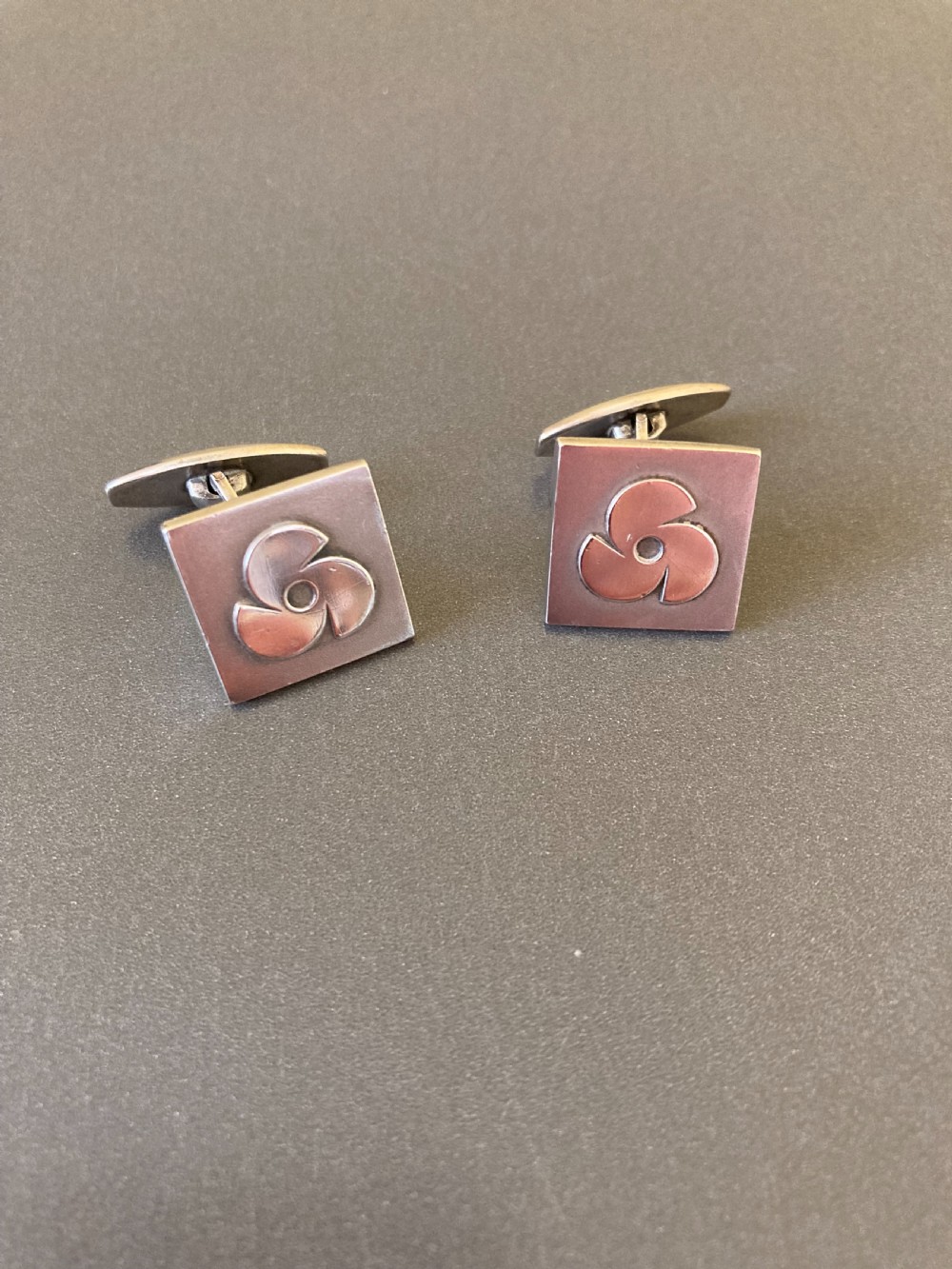 A pair of square Danish silver cufflinks featuring an abstract geometric pinwheel design, displayed in a dark hinged presentation box. View II