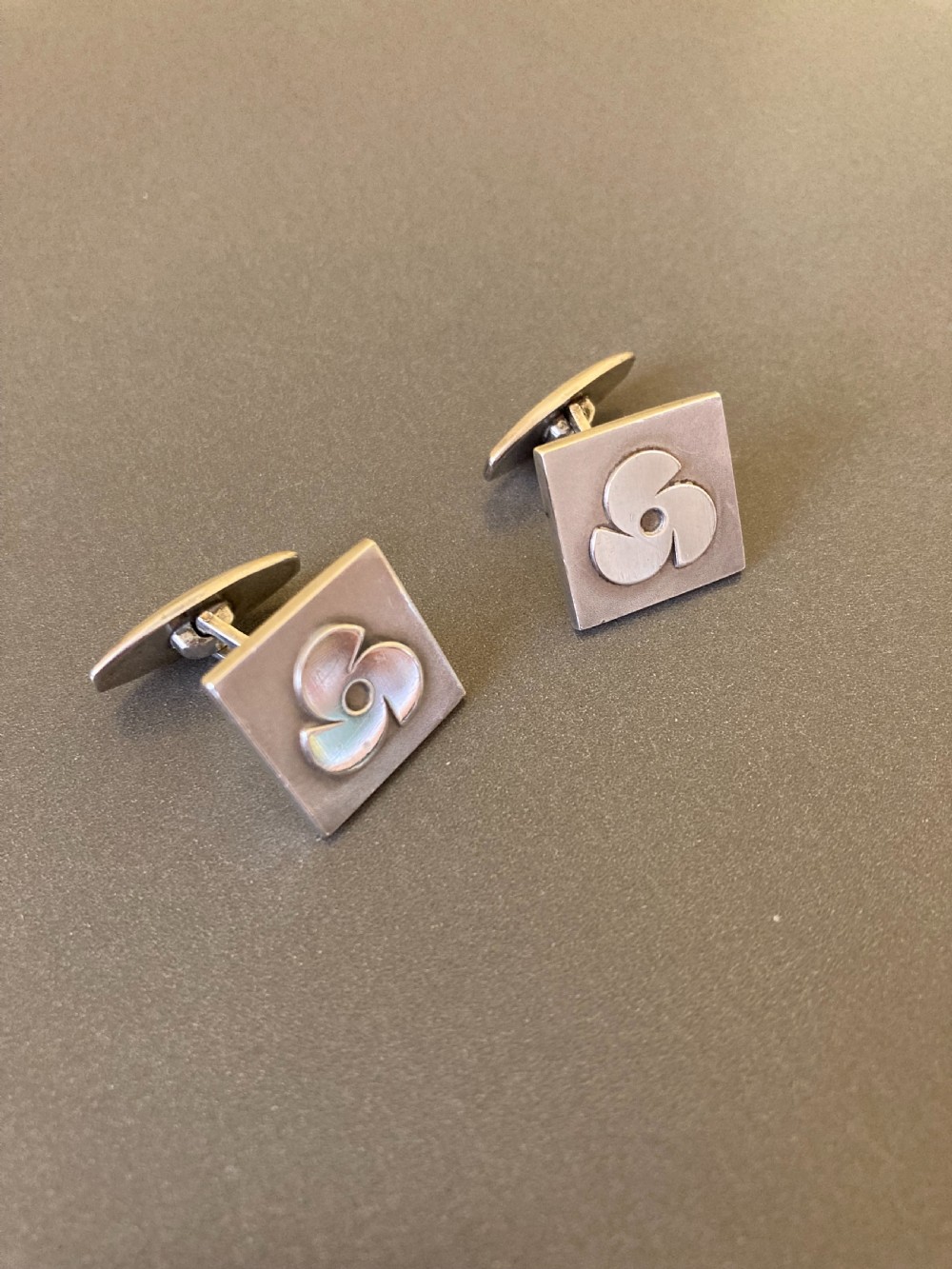 A pair of square Danish silver cufflinks featuring an abstract geometric pinwheel design, displayed in a dark hinged presentation box. View III