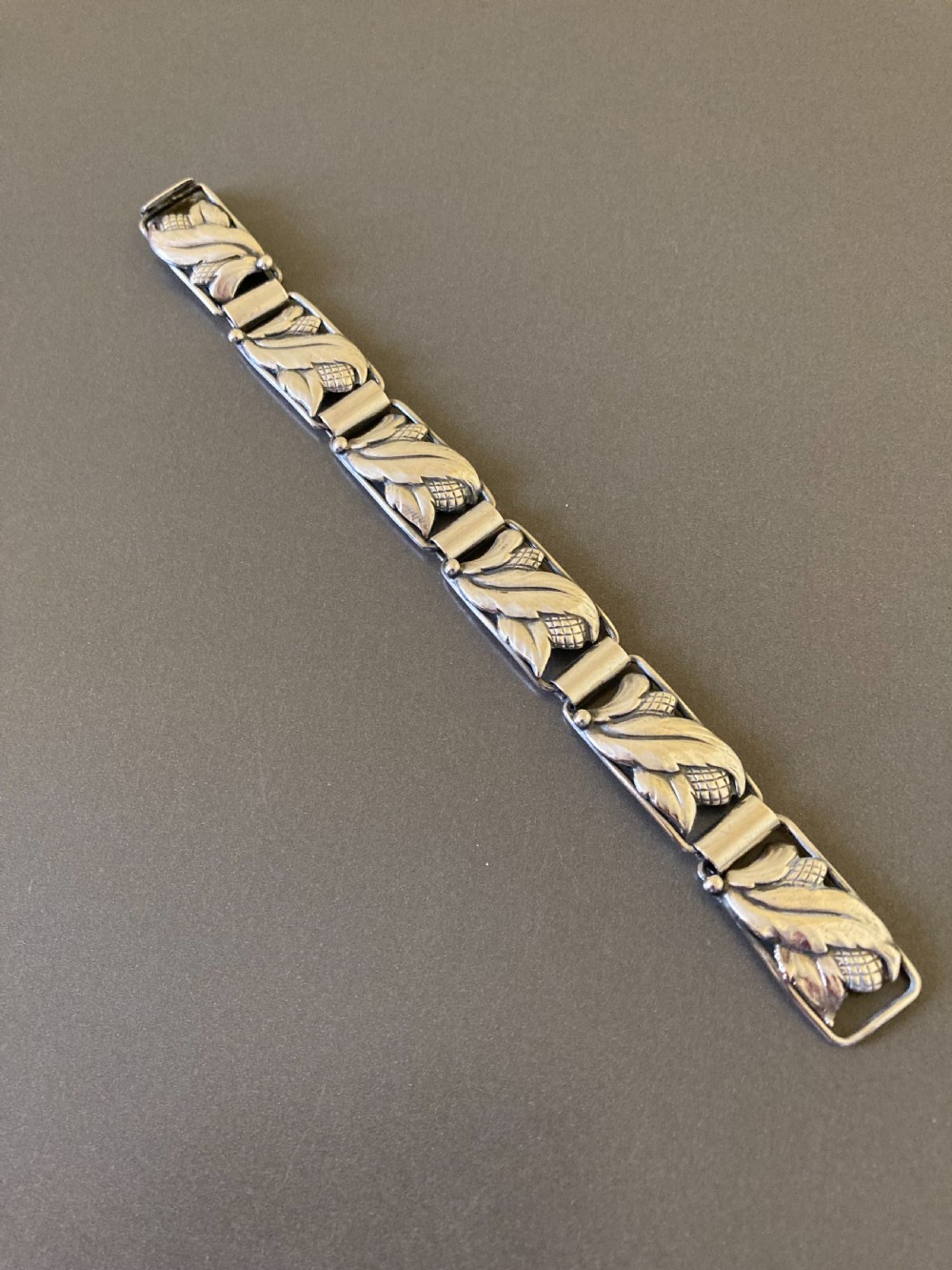 A segmented silver link bracelet featuring repeating organic botanical motifs in a mid-century Scandinavian style.