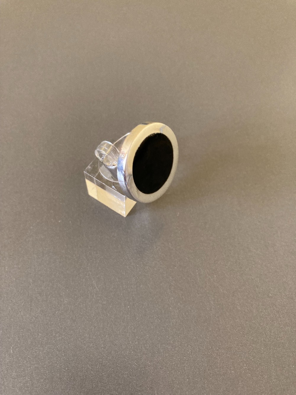 A round vintage Danish sterling silver ring featuring a central disc of black enamel, displayed inside a clear plastic ring box. View V