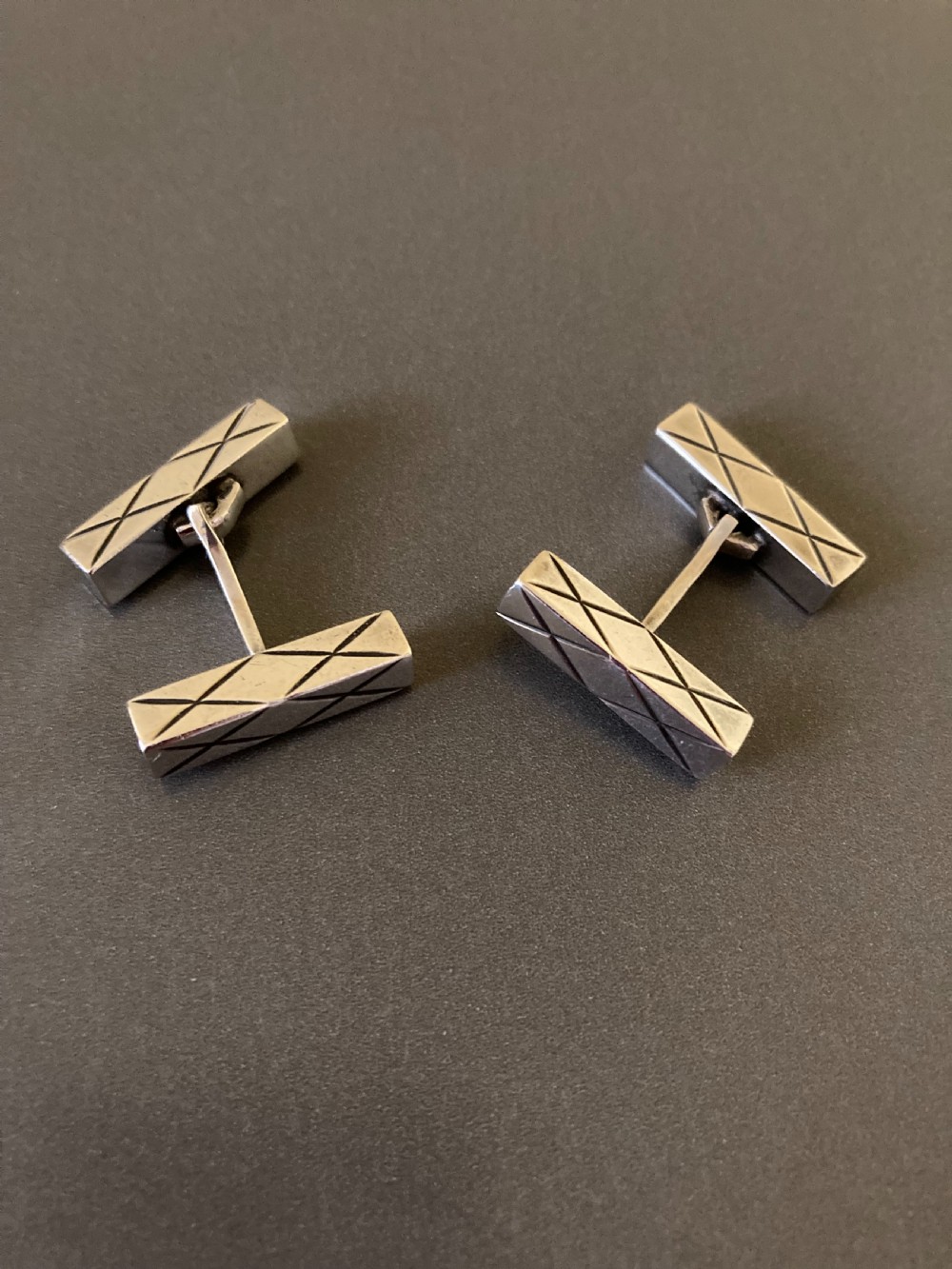 A pair of rectangular mid-century Danish silver cufflinks featuring engraved geometric line patterns.
