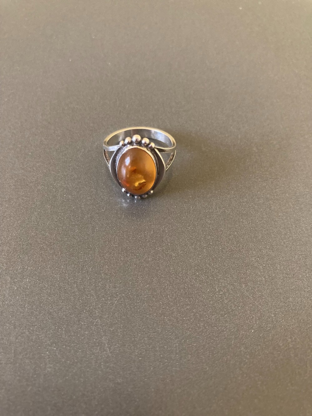 A vintage 1950s Danish sterling silver ring featuring a polished oval amber cabochon set with delicate granulation detailing. View II
