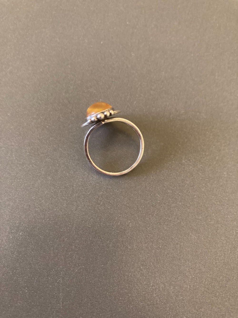 A vintage 1950s Danish sterling silver ring featuring a polished oval amber cabochon set with delicate granulation detailing. View III