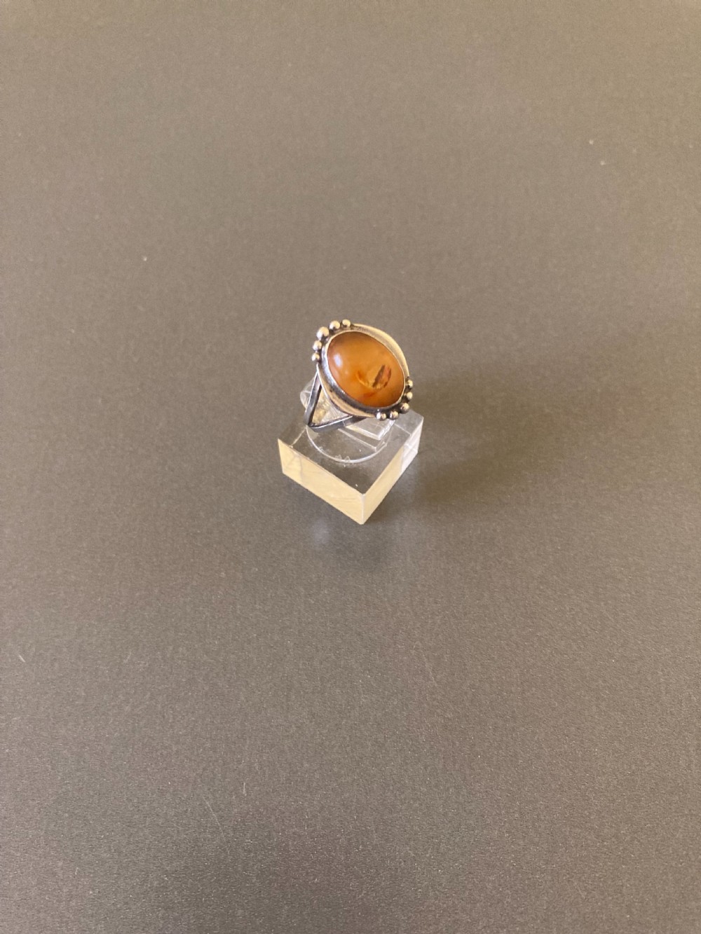A vintage 1950s Danish sterling silver ring featuring a polished oval amber cabochon set with delicate granulation detailing. View IV