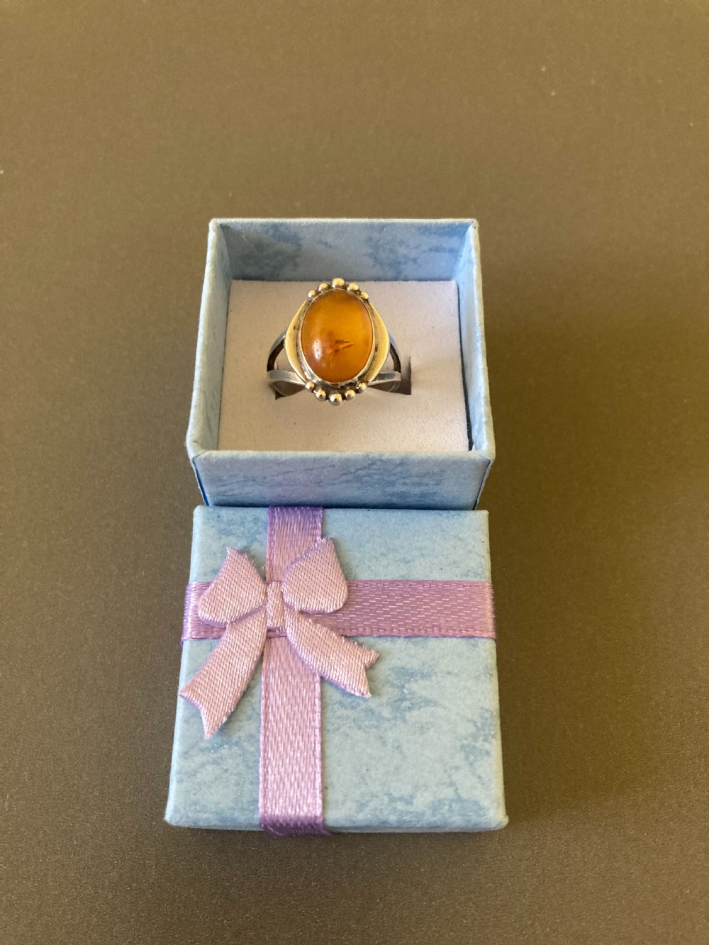 A vintage 1950s Danish sterling silver ring featuring a polished oval amber cabochon set with delicate granulation detailing. View VI