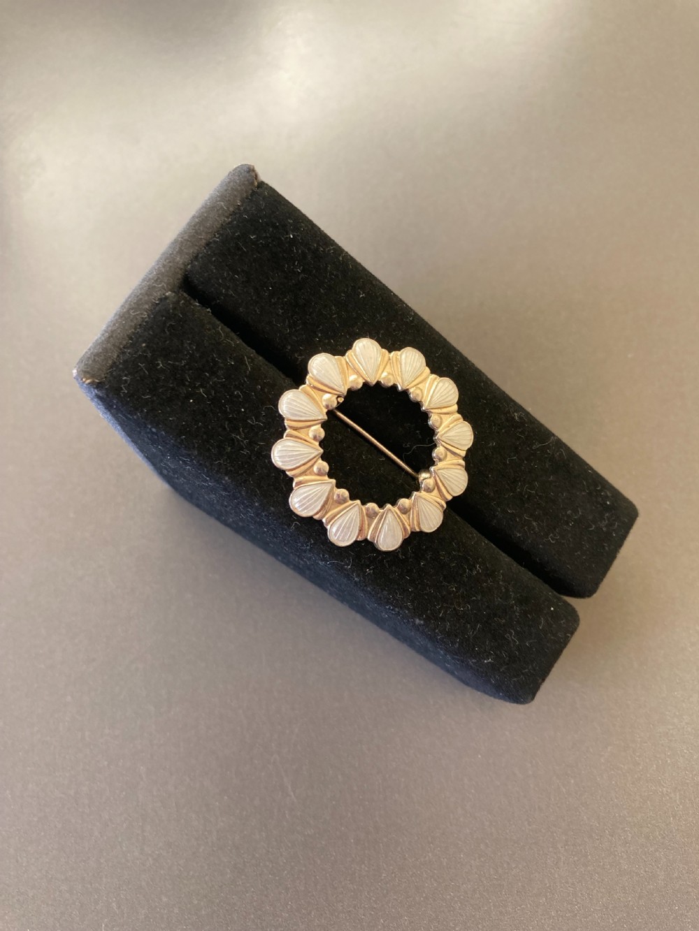 A circular vintage Danish silver gilt brooch featuring a repeating pattern of white enamel teardrop elements. View II