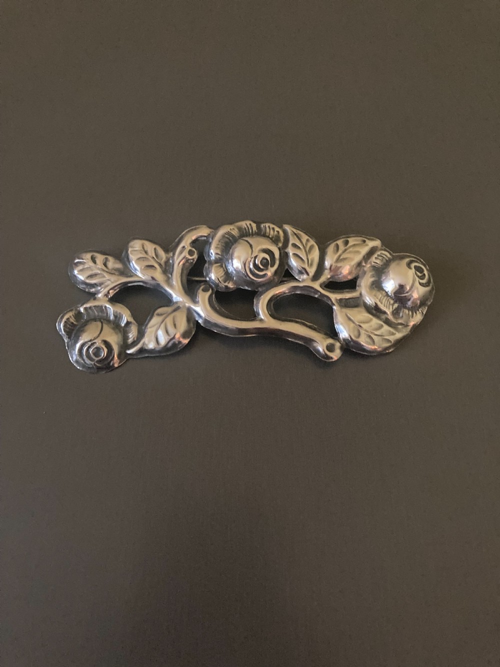 A 1920s Danish silver brooch featuring an openwork floral design of three sculpted rose blossoms and leaves.