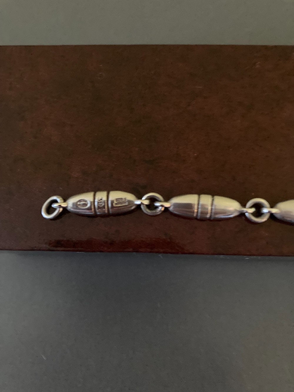 A vintage Georg Jensen sterling silver link bracelet featuring elongated bullet-shaped segments connected by small rings against a dark grey background. View VI