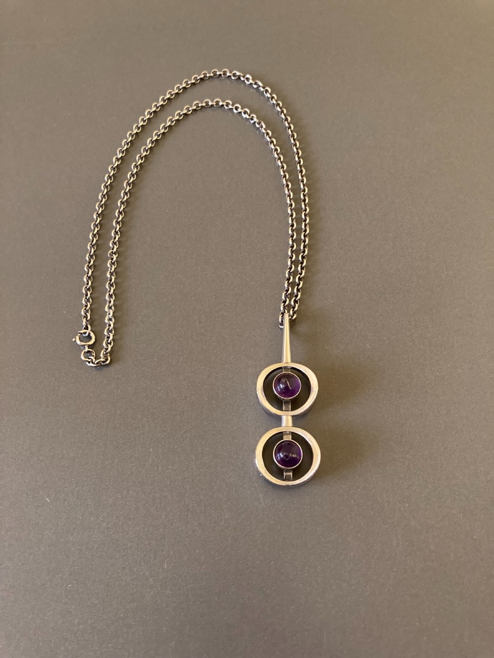 A vintage Danish modernist sterling silver pendant featuring two circular elements set with cabochon amethysts, suspended from a matching silver chain. View II