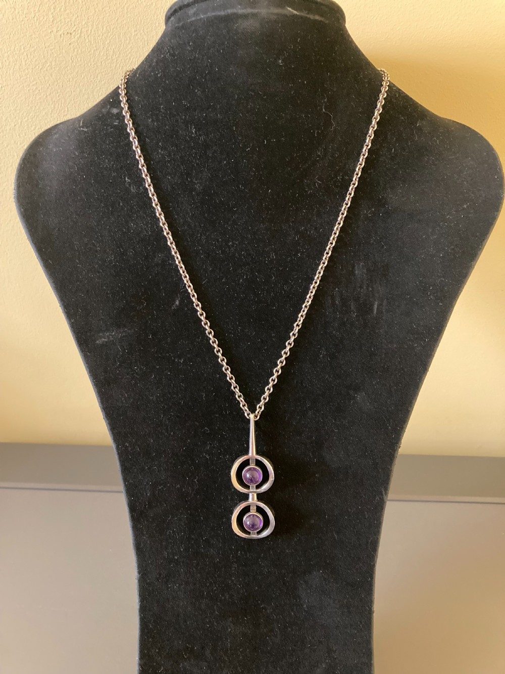 A vintage Danish modernist sterling silver pendant featuring two circular elements set with cabochon amethysts, suspended from a matching silver chain. View III