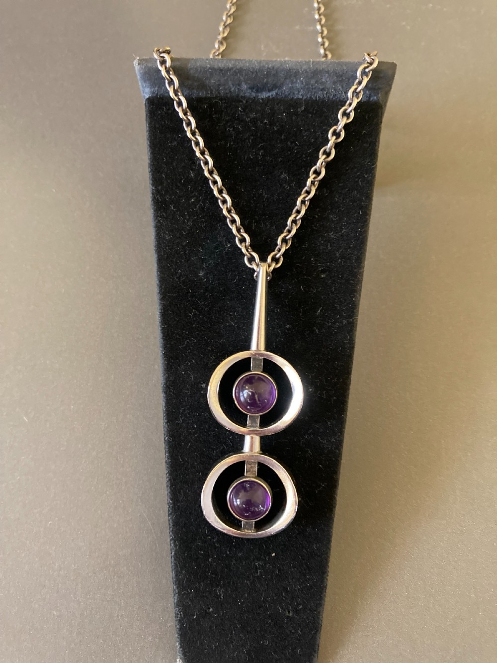 A vintage Danish modernist sterling silver pendant featuring two circular elements set with cabochon amethysts, suspended from a matching silver chain. View IV