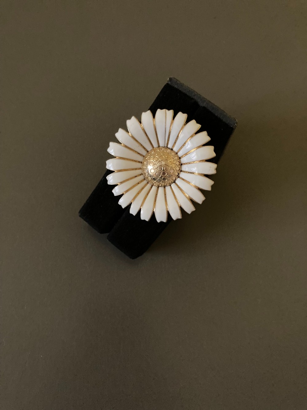 A circular vintage brooch in the shape of a white daisy with a gold-textured centre. View III