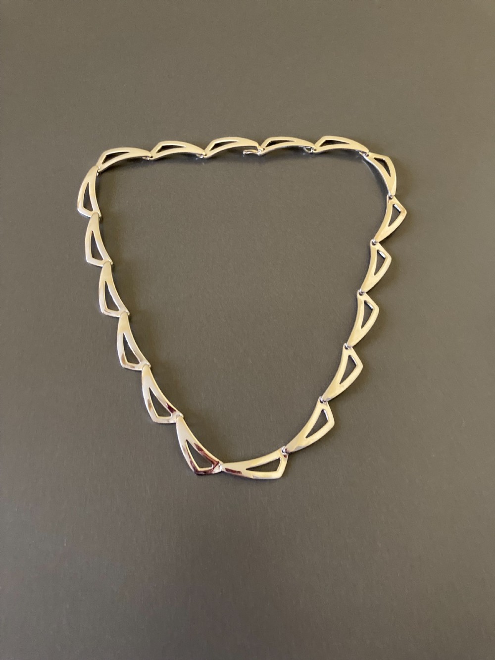 A vintage 1960s Danish sterling silver necklace featuring an articulated sequence of open triangular geometric links.